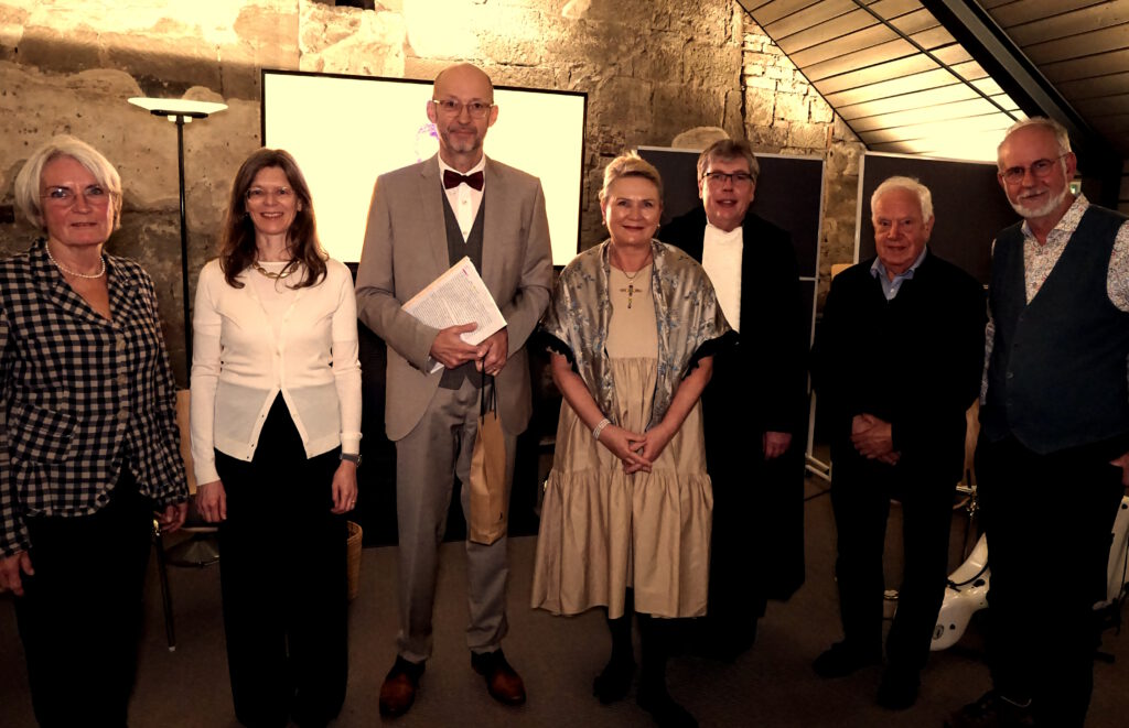 Ein Gruppenfoto mit den an der Lesung beteiligten oder verantwortlichen Personen. Es wurde im Medienraum des Infozentrums im Kloster Maulbronn aufgenommen. Die Personen haben sich für das Gruppenfoto positioniert und schauen in die Kamera.